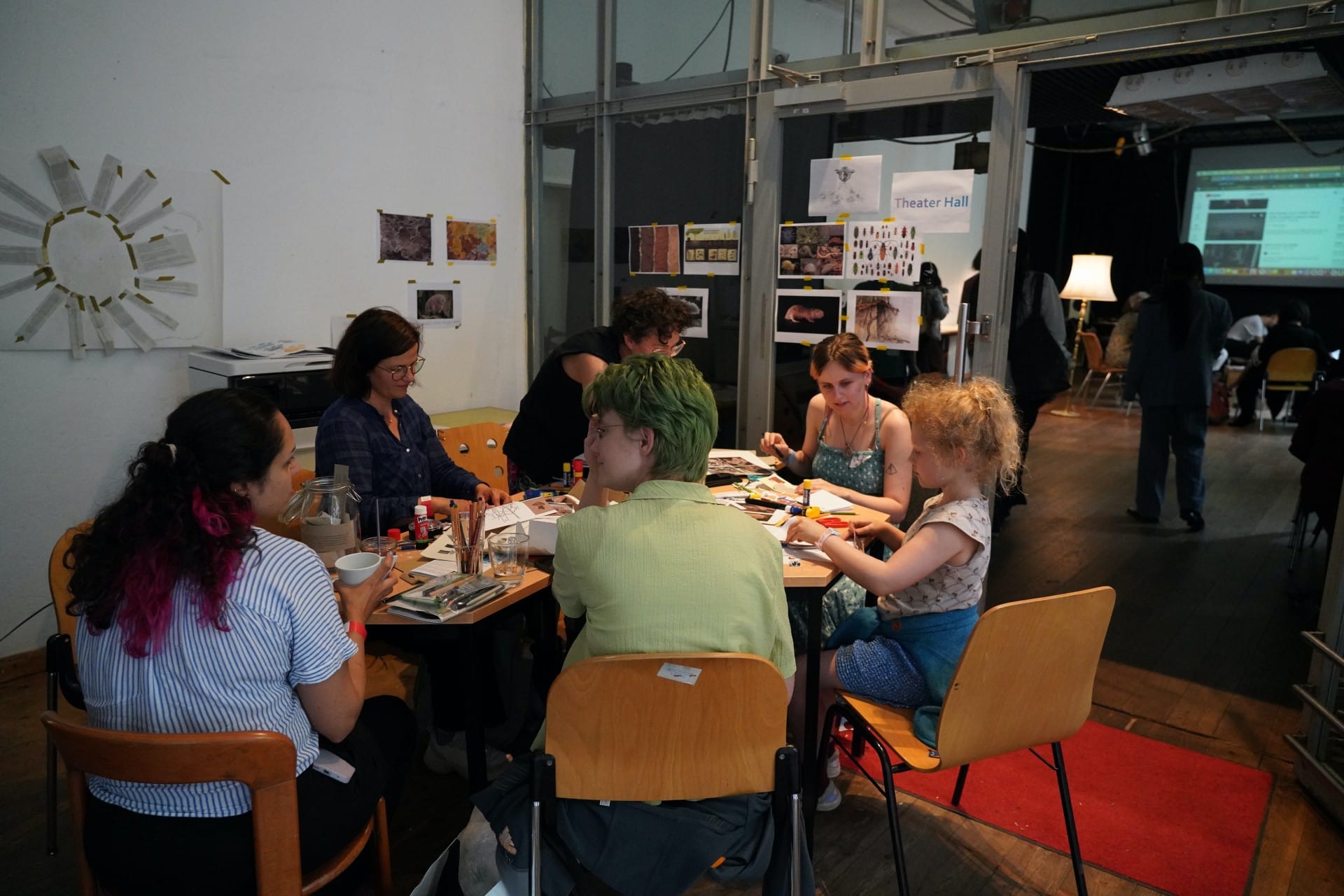 people seated at a table talking and drawing