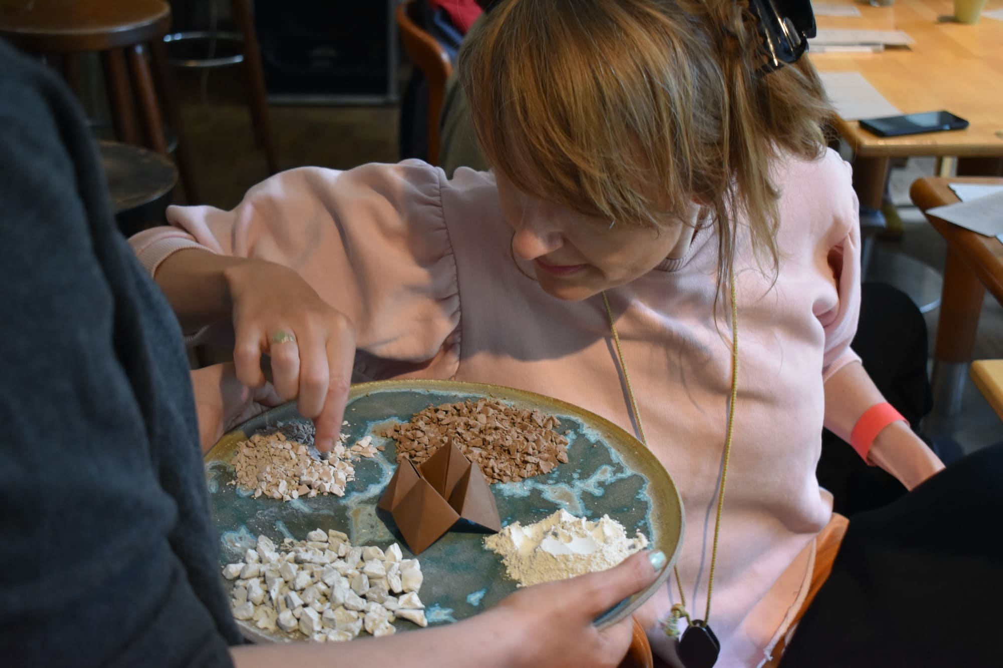 a woman touches chalk like material on a tray