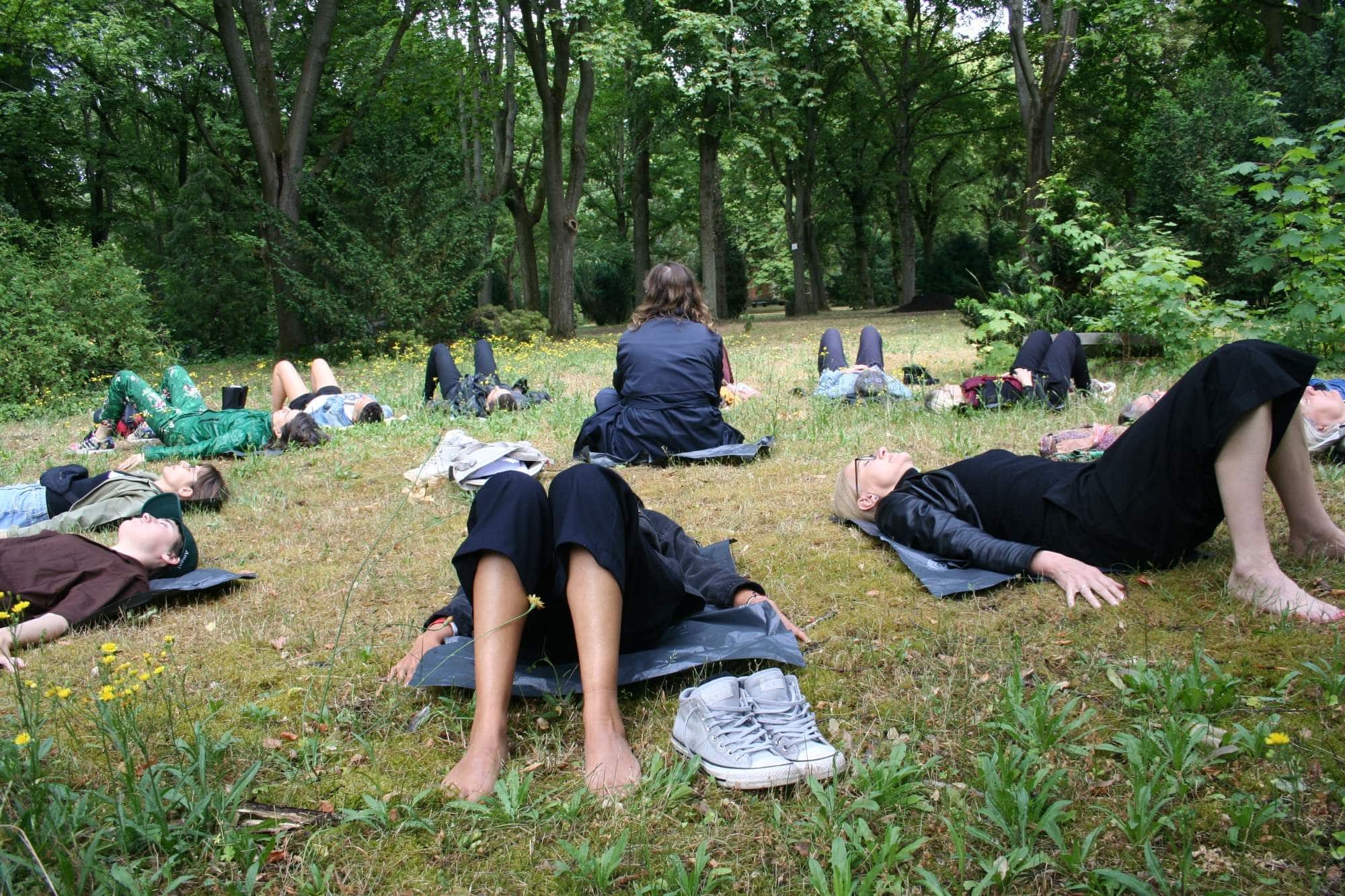 a group of people lay on the ground in a park with trees in the background