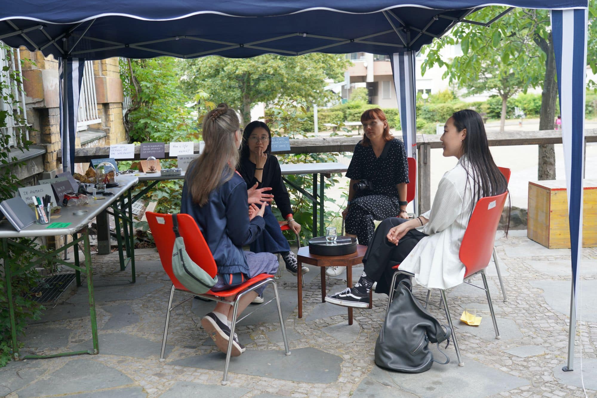 four women seated outside under an awning