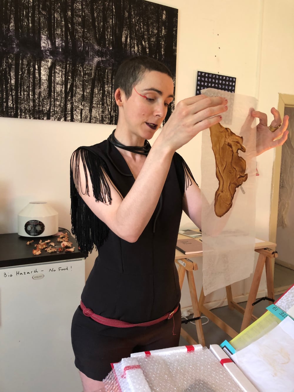 a woman (Margherita Pevere) holding a piece of translucent vellum with a brown abstract form on it