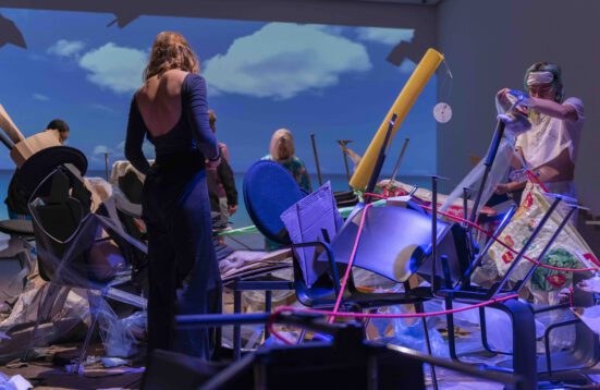 people building an installation of found material. Background: a projection of sea and clouds