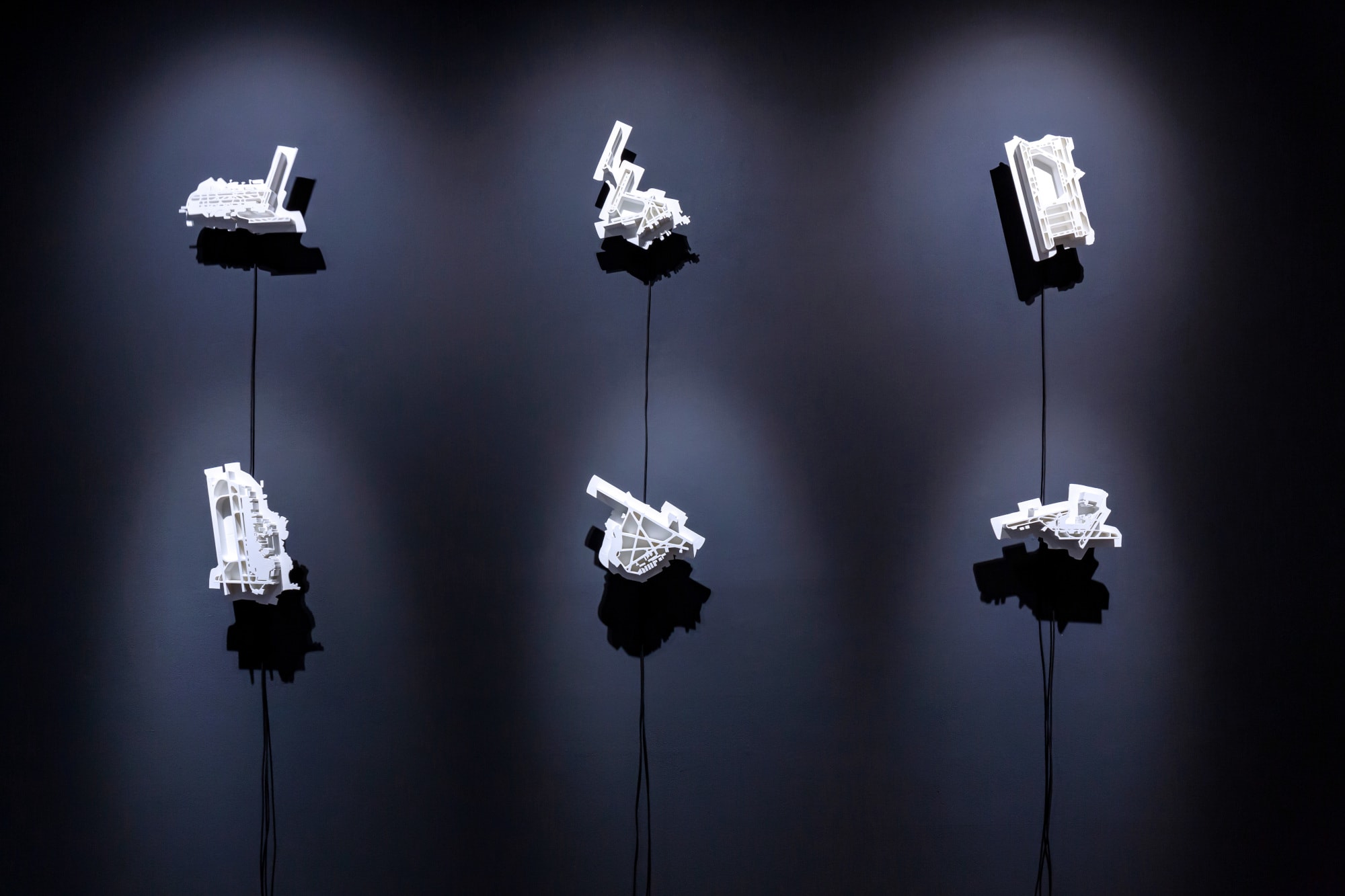 Six Aeroglyphs, white architectural models of airports on a grey wall