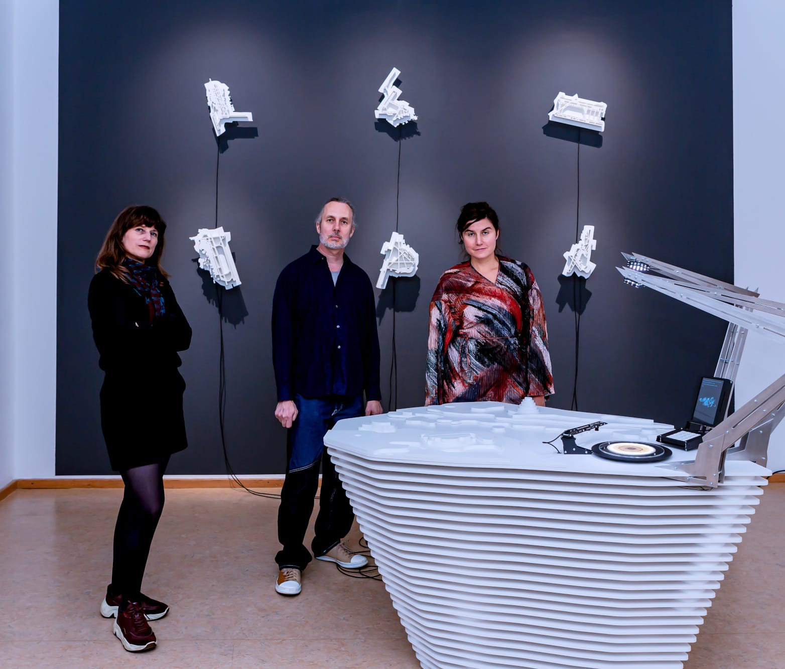 Three people standing in front of artwork