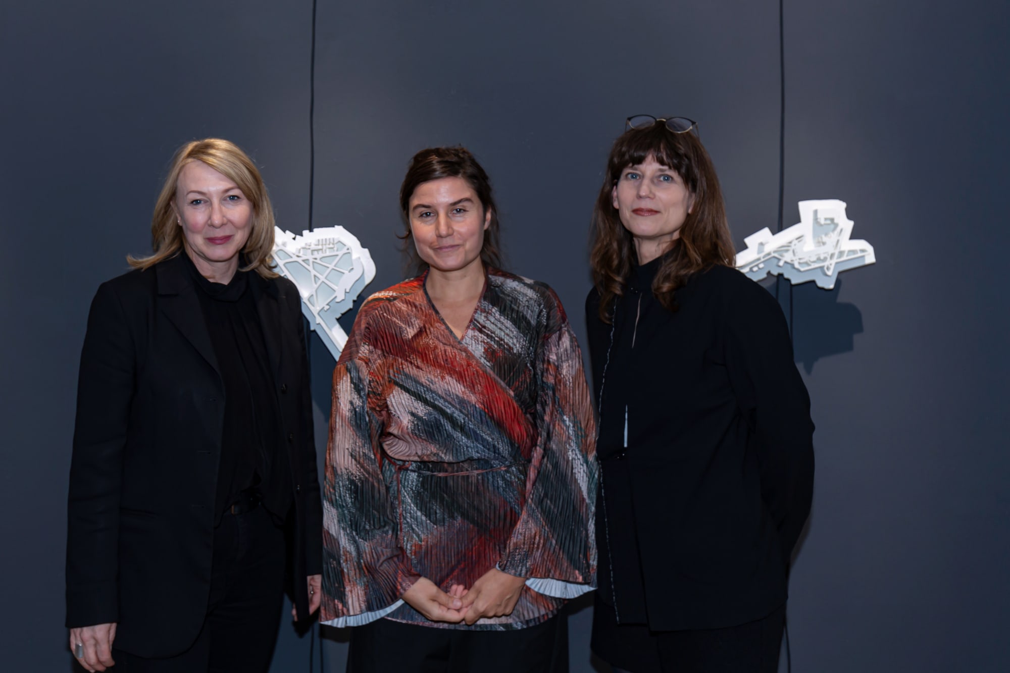 Three people standing in front of artwork