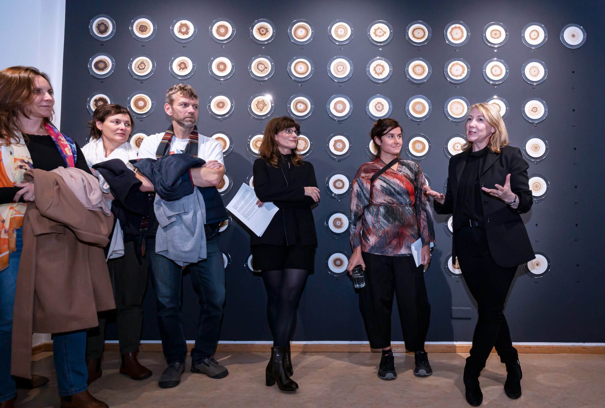 People listening to a person speaking at the opening of the exhibition
