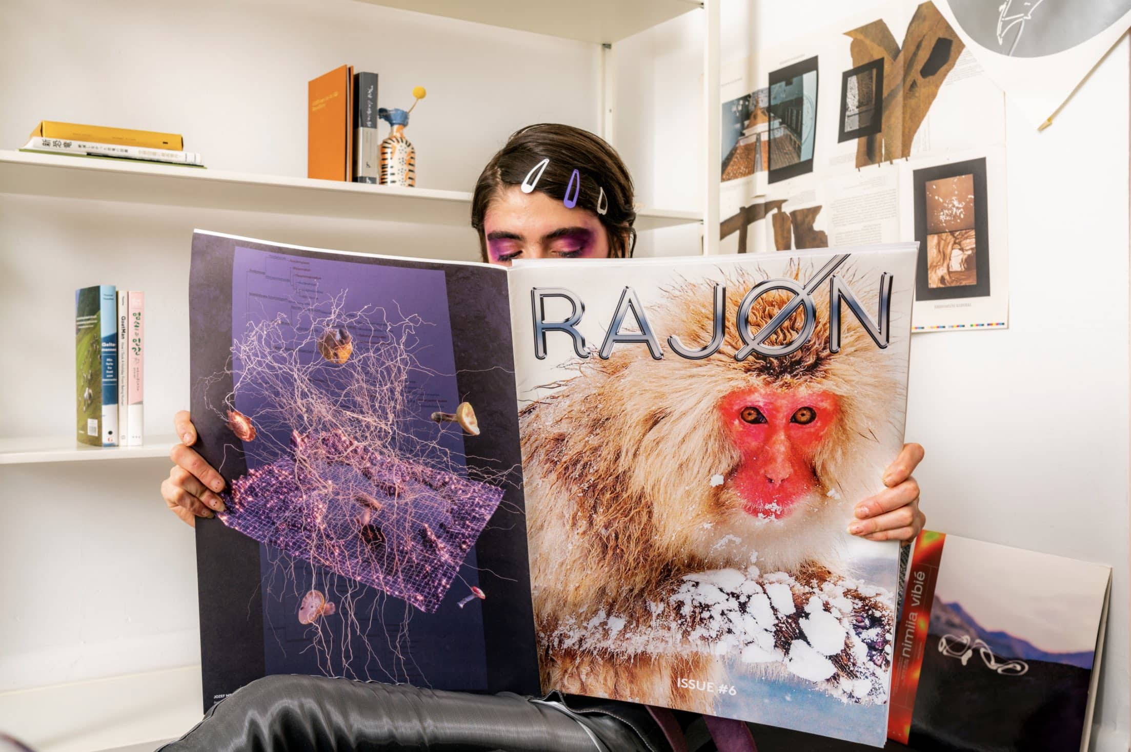 A woman reading a Zine with a monkey and the word RAJON written on the coverr