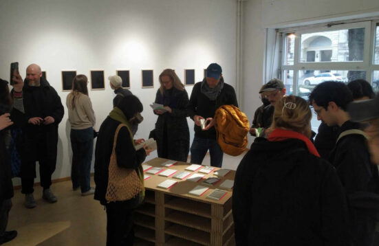 People in a gallery looking at artwork and books