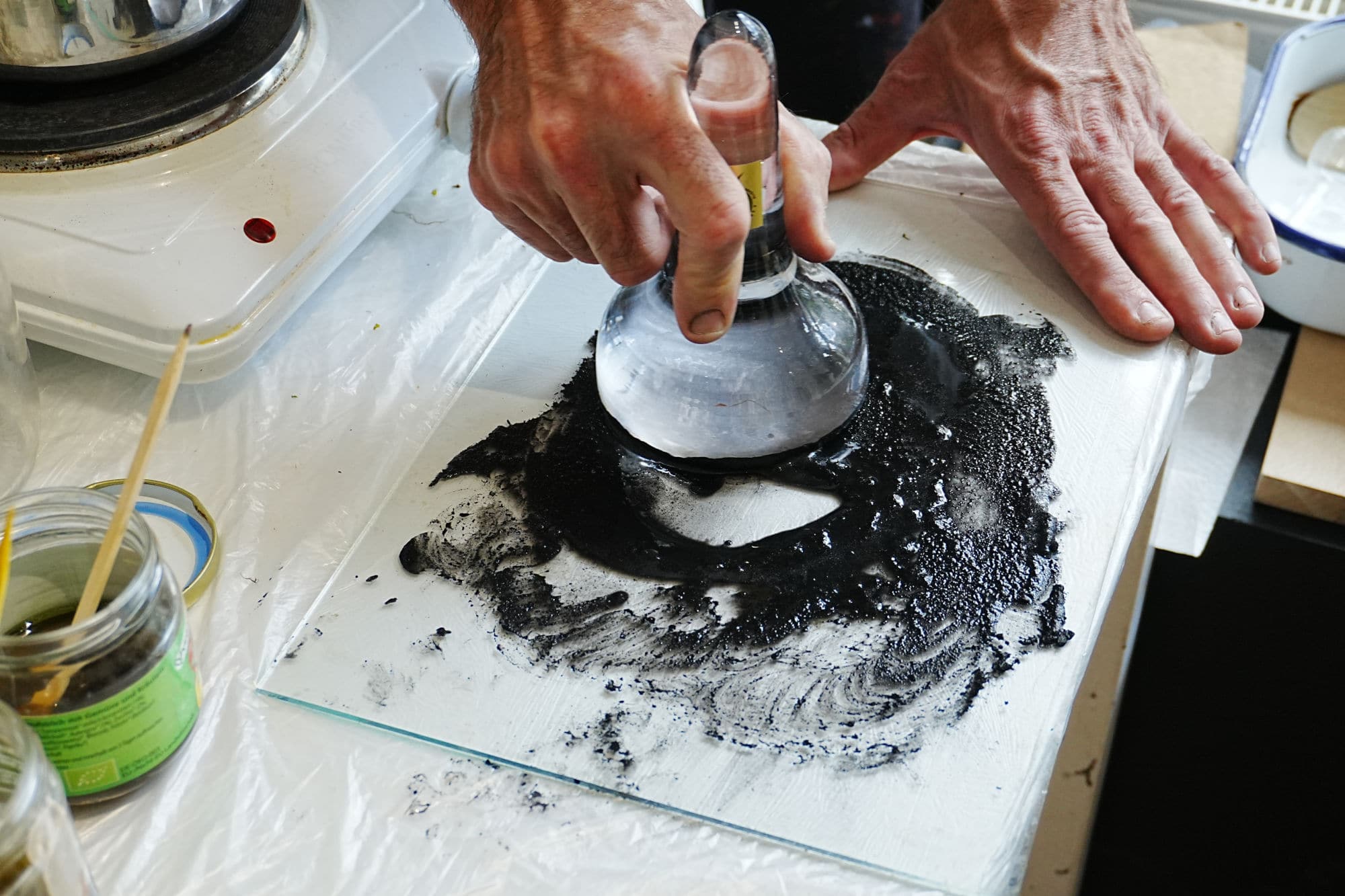 eine Hand, die einen gläsernen Stößel hält, der Schwarz in