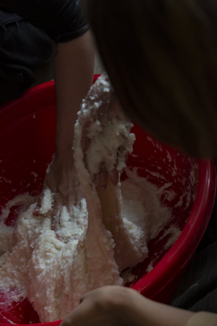 hands kneeding dough in a red pot