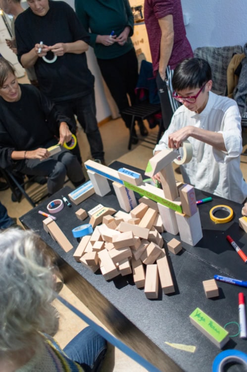 people building with wooden blocks