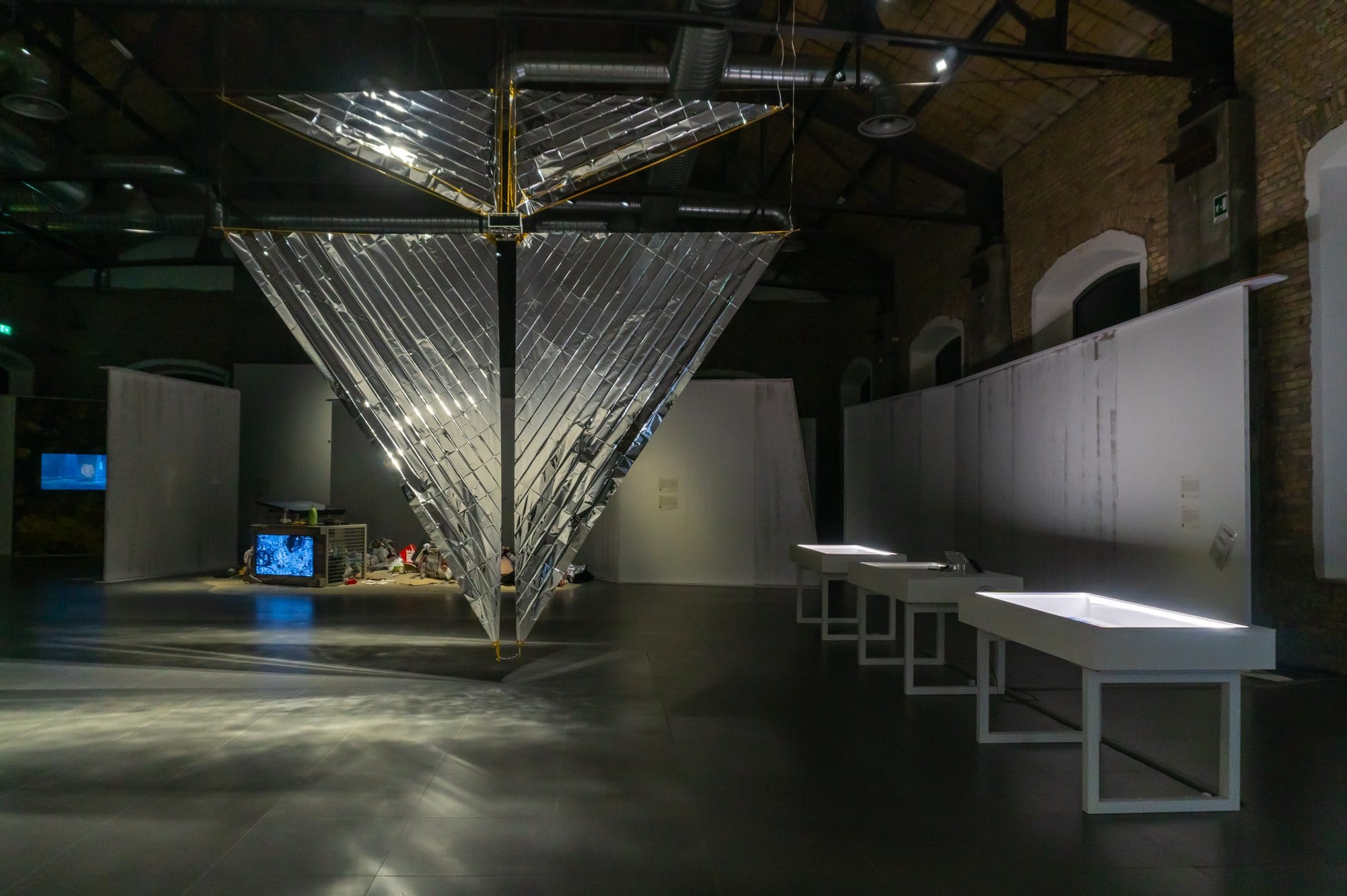 a silver form of two triangles, which is a model of a solar sail in an exhibition room