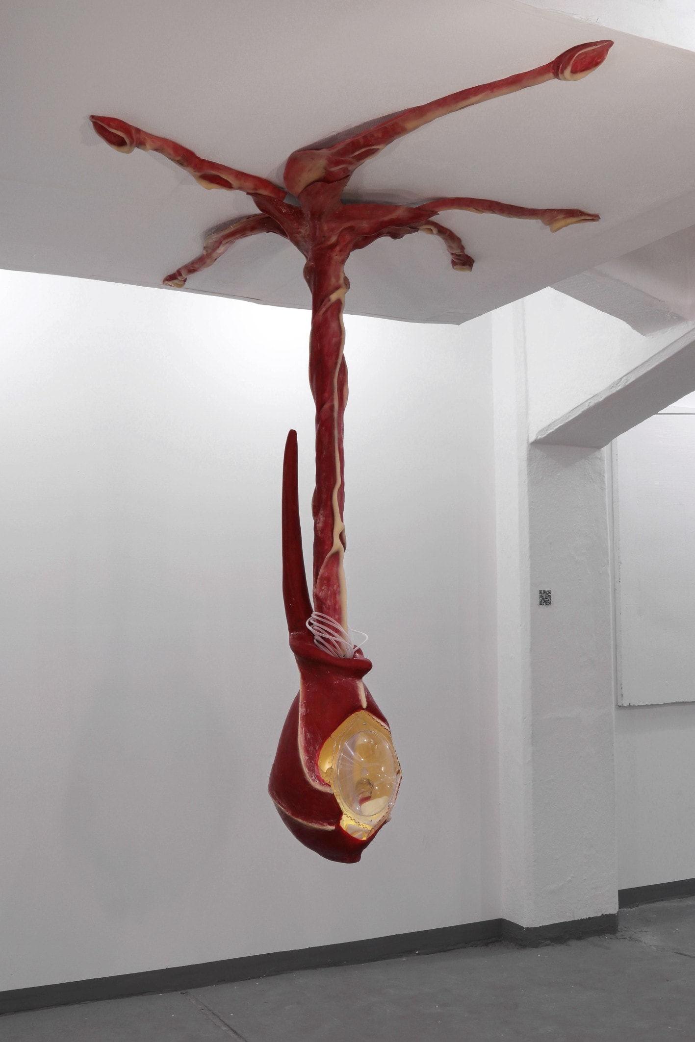 a ted and yellow sculpture handing from the ceiling, the lower part has a transparent container
