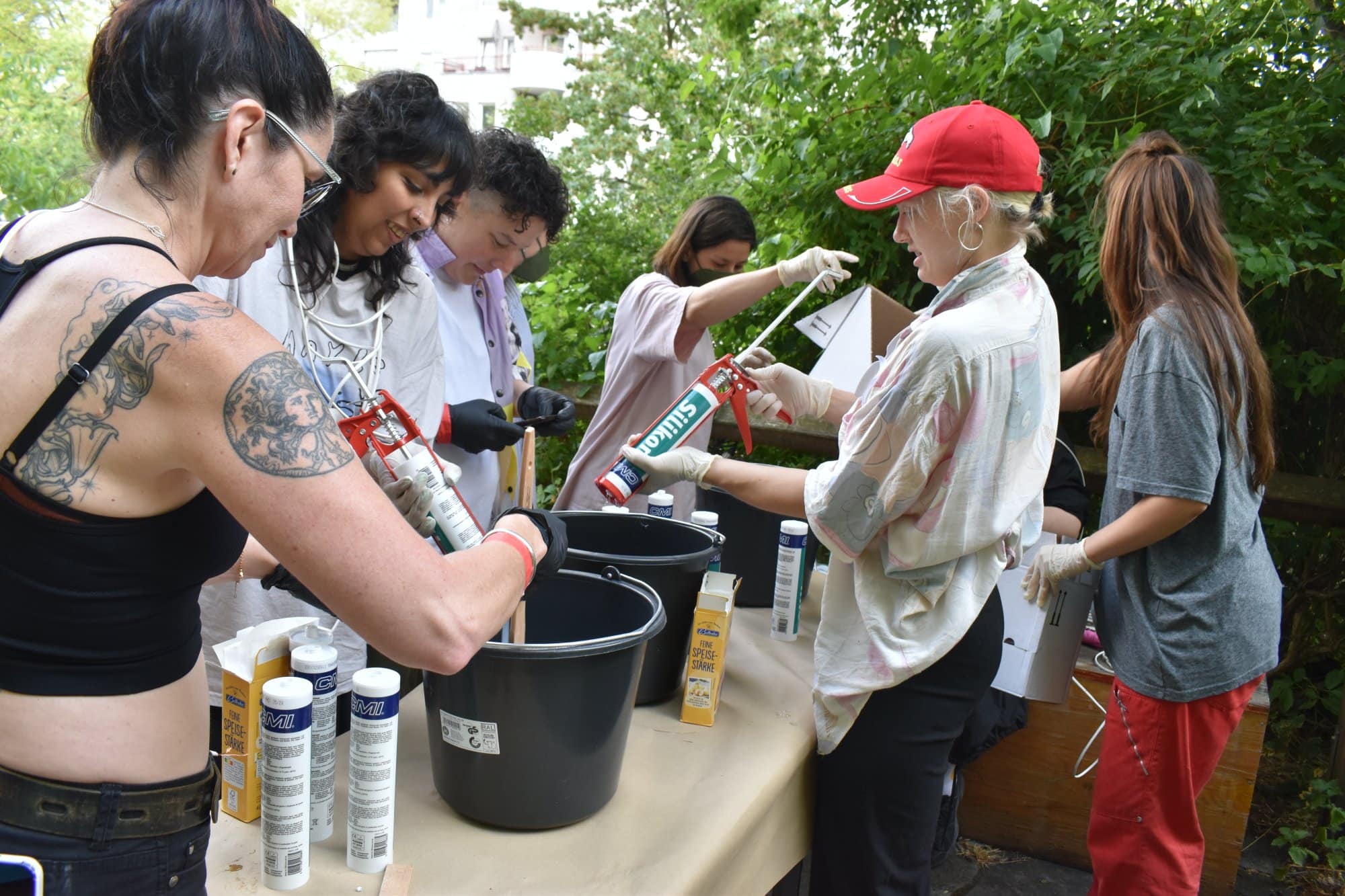 a group of women squeezing silicone caulk into black buckets