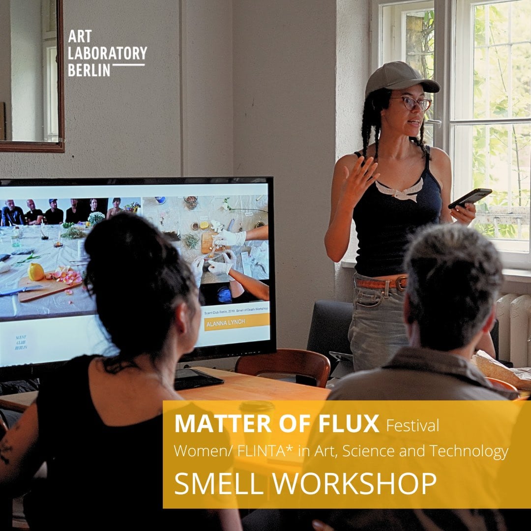a person standing reads aloud while holding a smart phone. other people sit and listen the Words:" Matter of Flux Festival Festival Women/FLINTA* in Art, Science and Technology Smell Workshop"