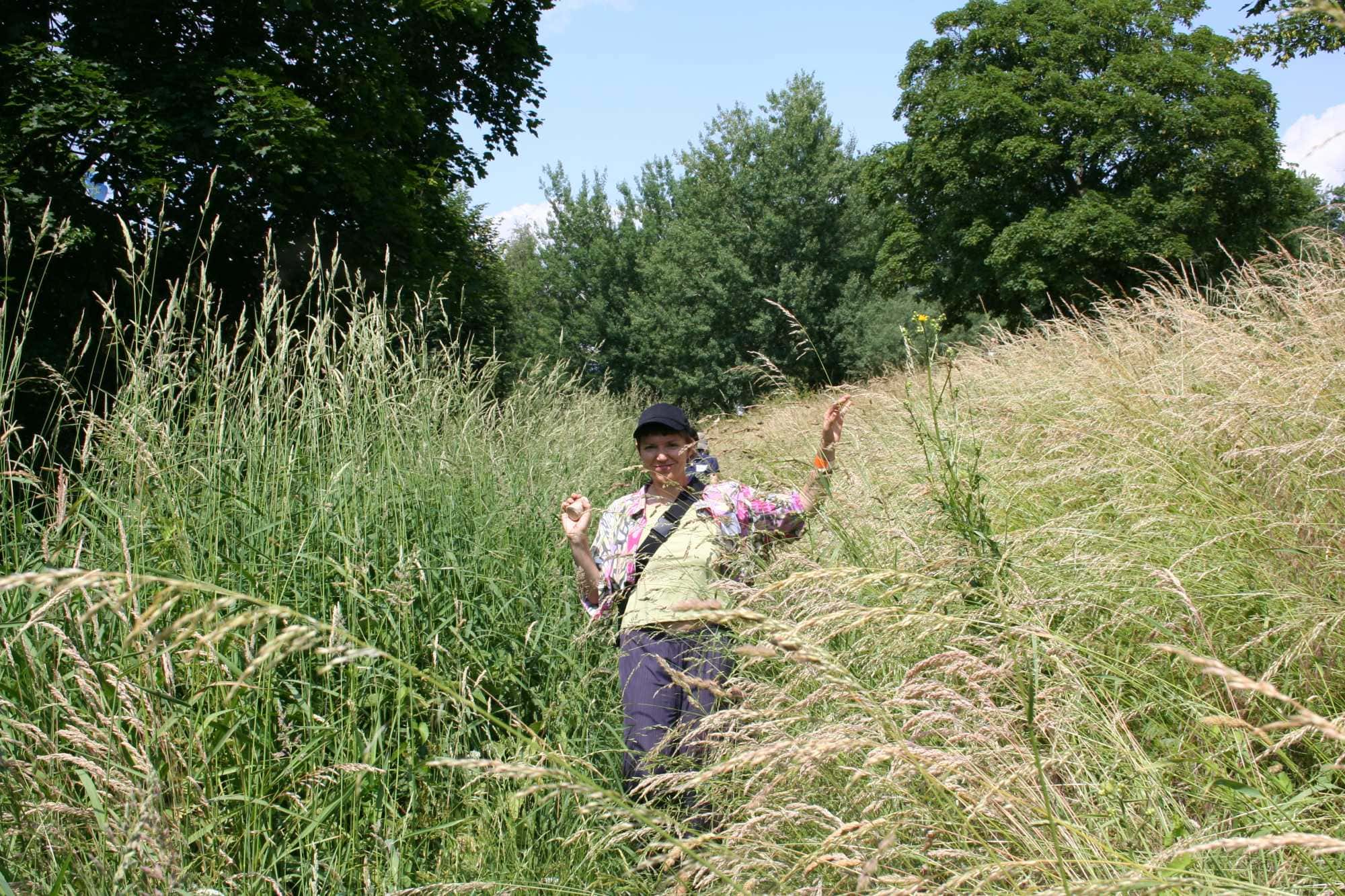 a woman in high grass. tress in the background