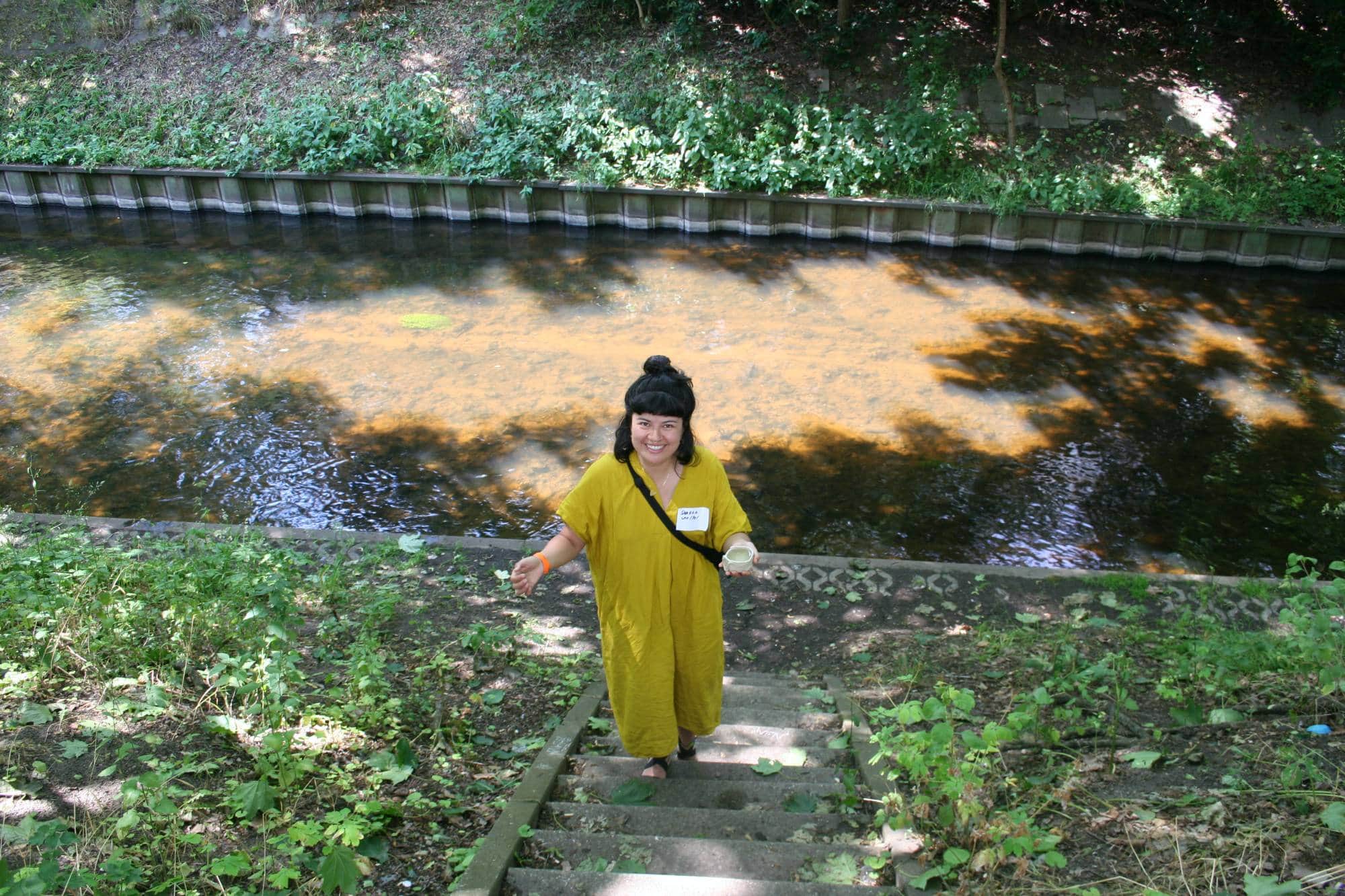a woman standing on stairs on the bank of a small river or canal
