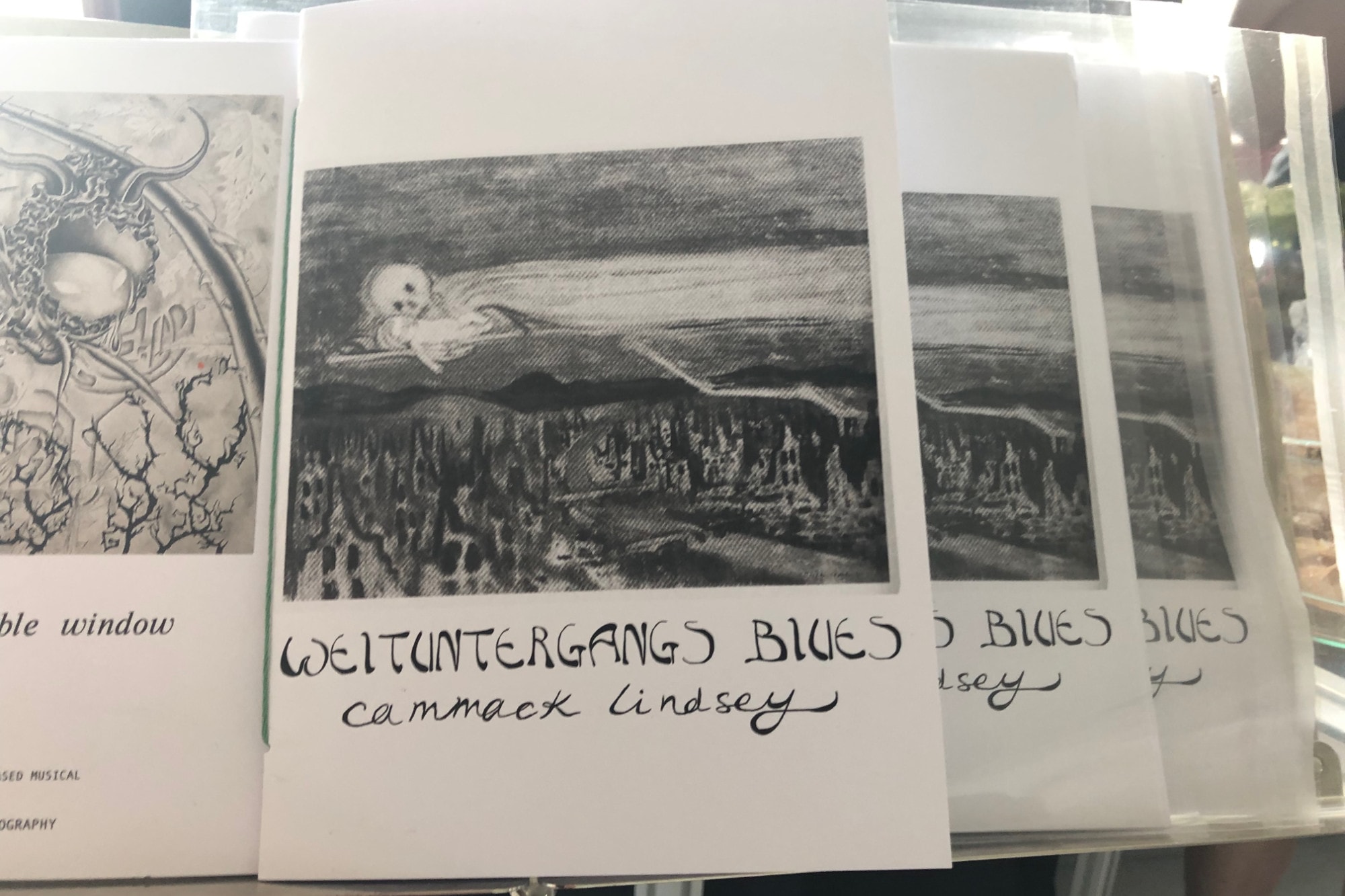 a set of prints on paper a form of a flying ghosts or skeleton and text: WEITUNTERGANGS BLUES Cammack Lindsey 