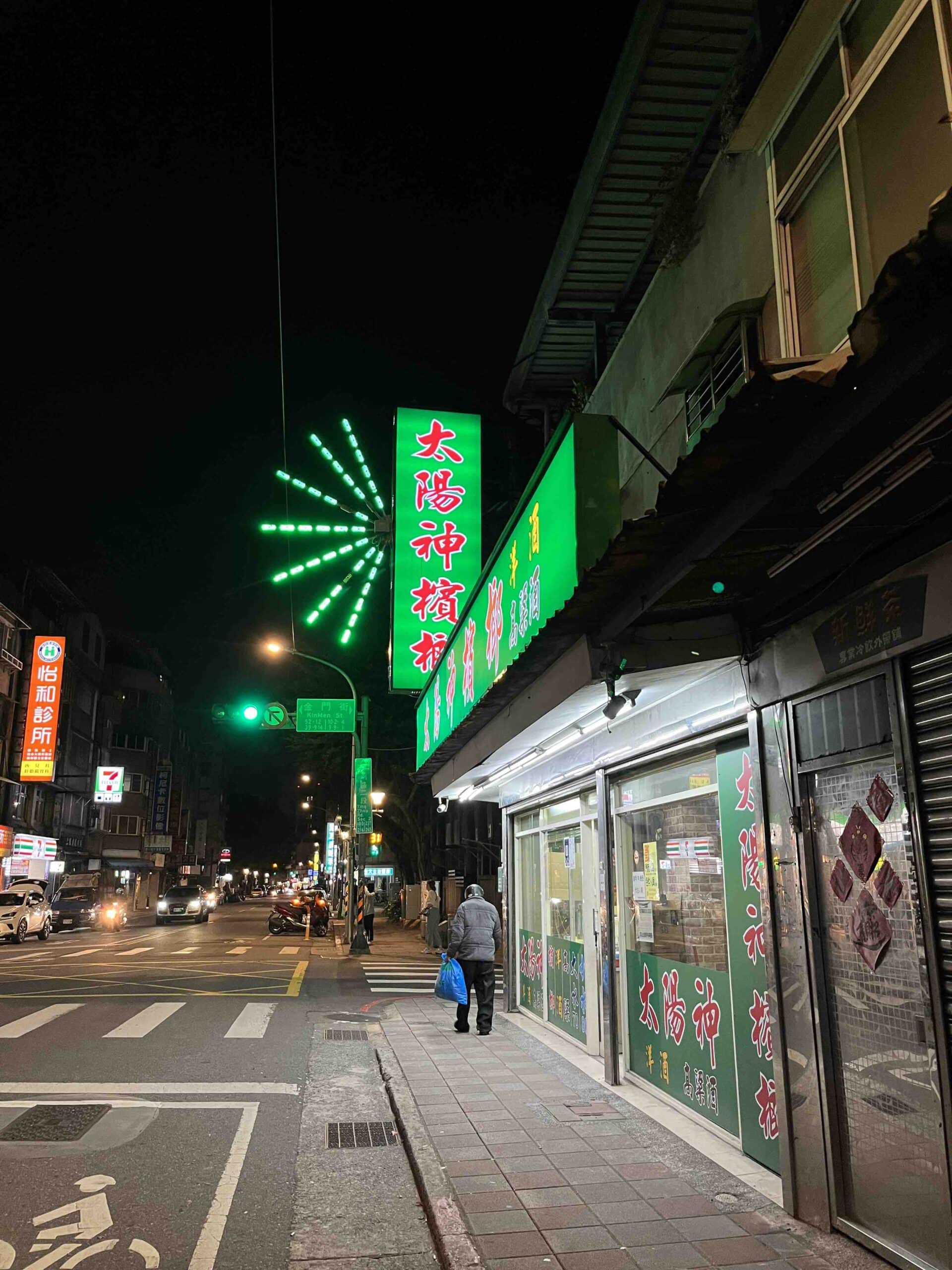 a street an night with a green sign with Chinese characters