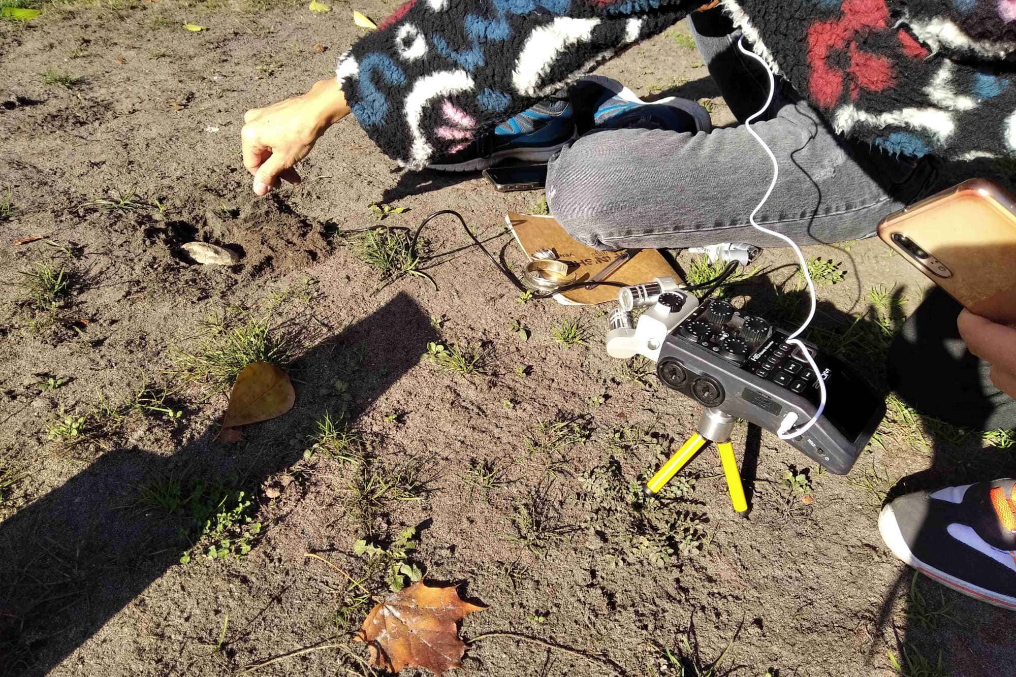 a person and sound recorder touching the soil