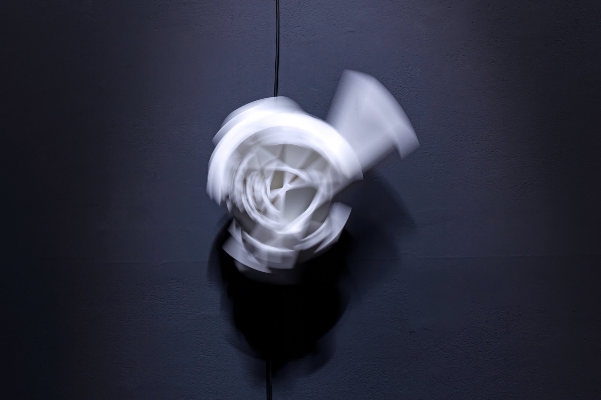 a blurry turn of a white architectural model turning on a grey wall