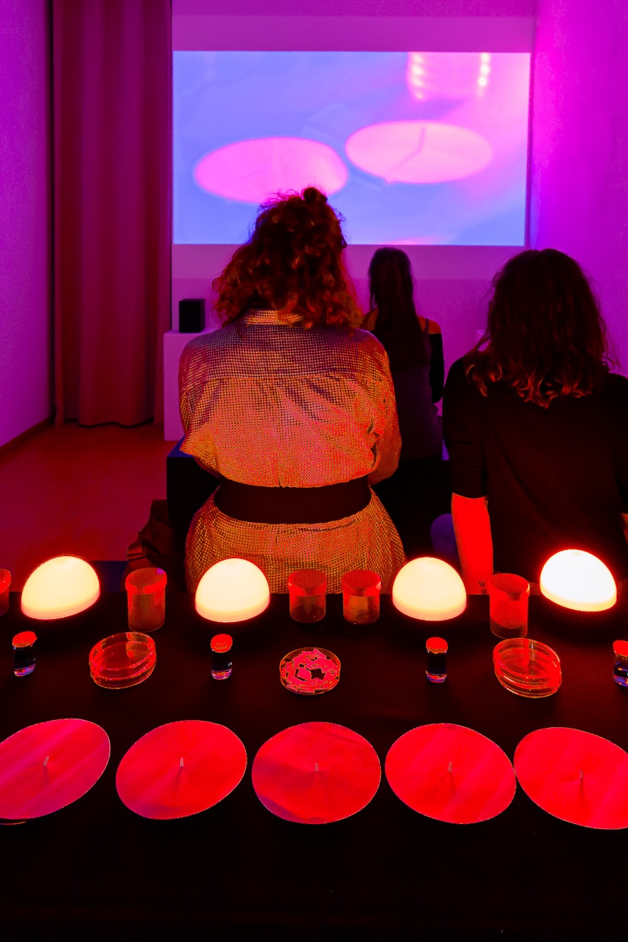people sitting watching the film 'Holding Patterns' table with red darkroom lights in the foregraound
