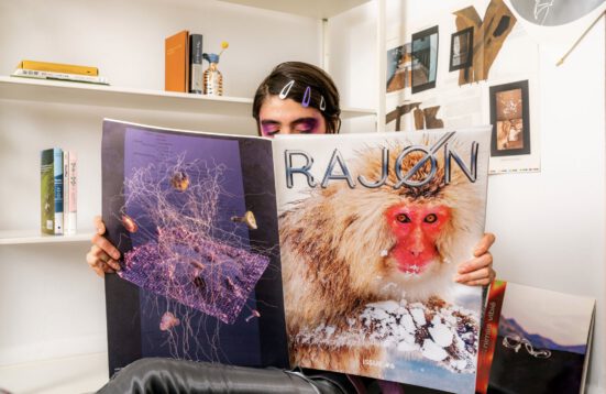 A woman reading a Zine with a monkey and the word RAJON written on the coverr