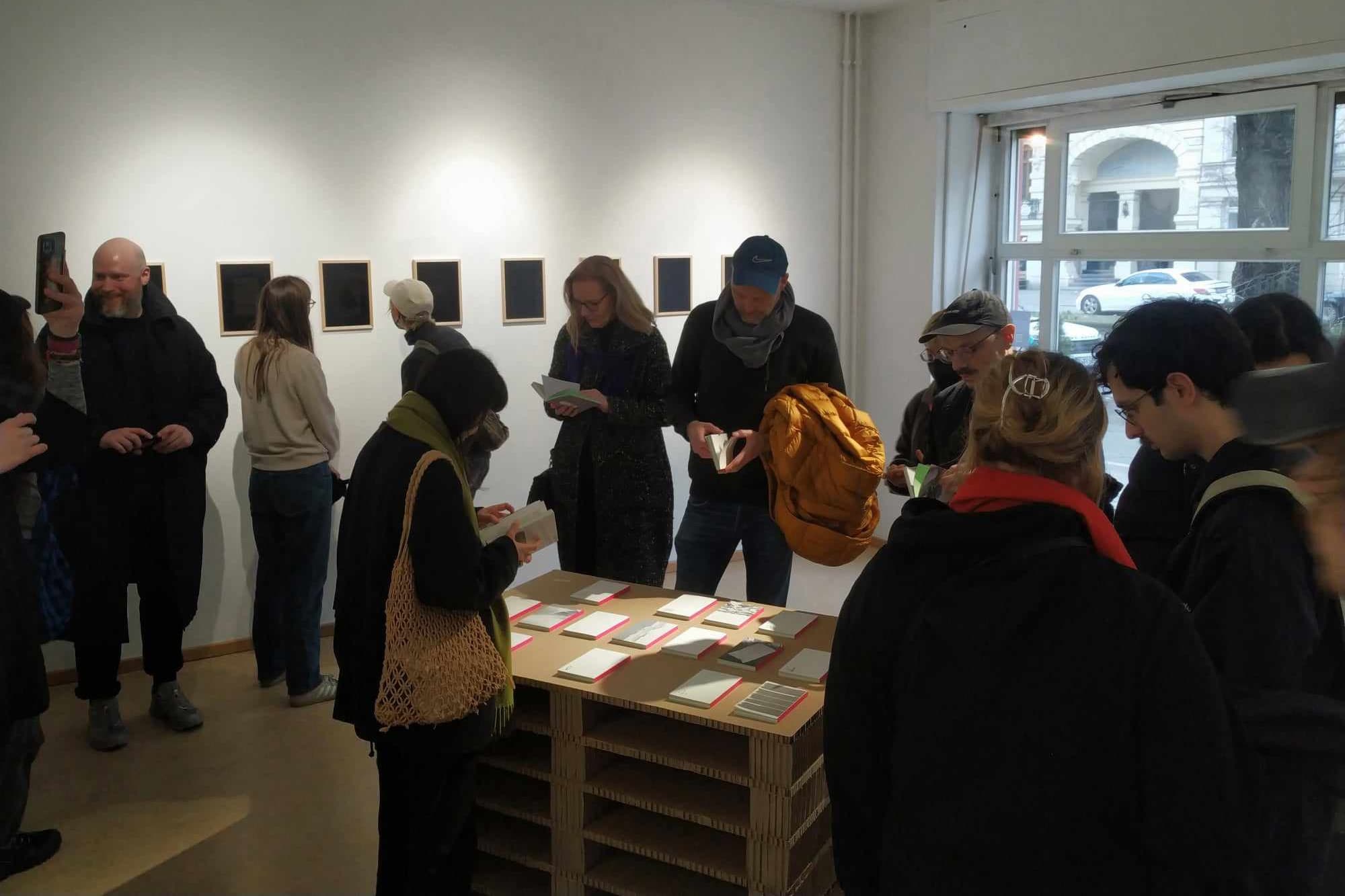 People in a gallery looking at artwork and books
