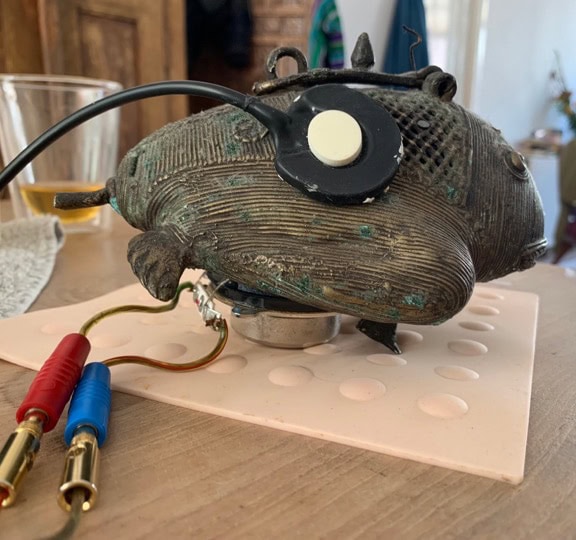 a sculpture of a small frog with microphone and small speaker attached