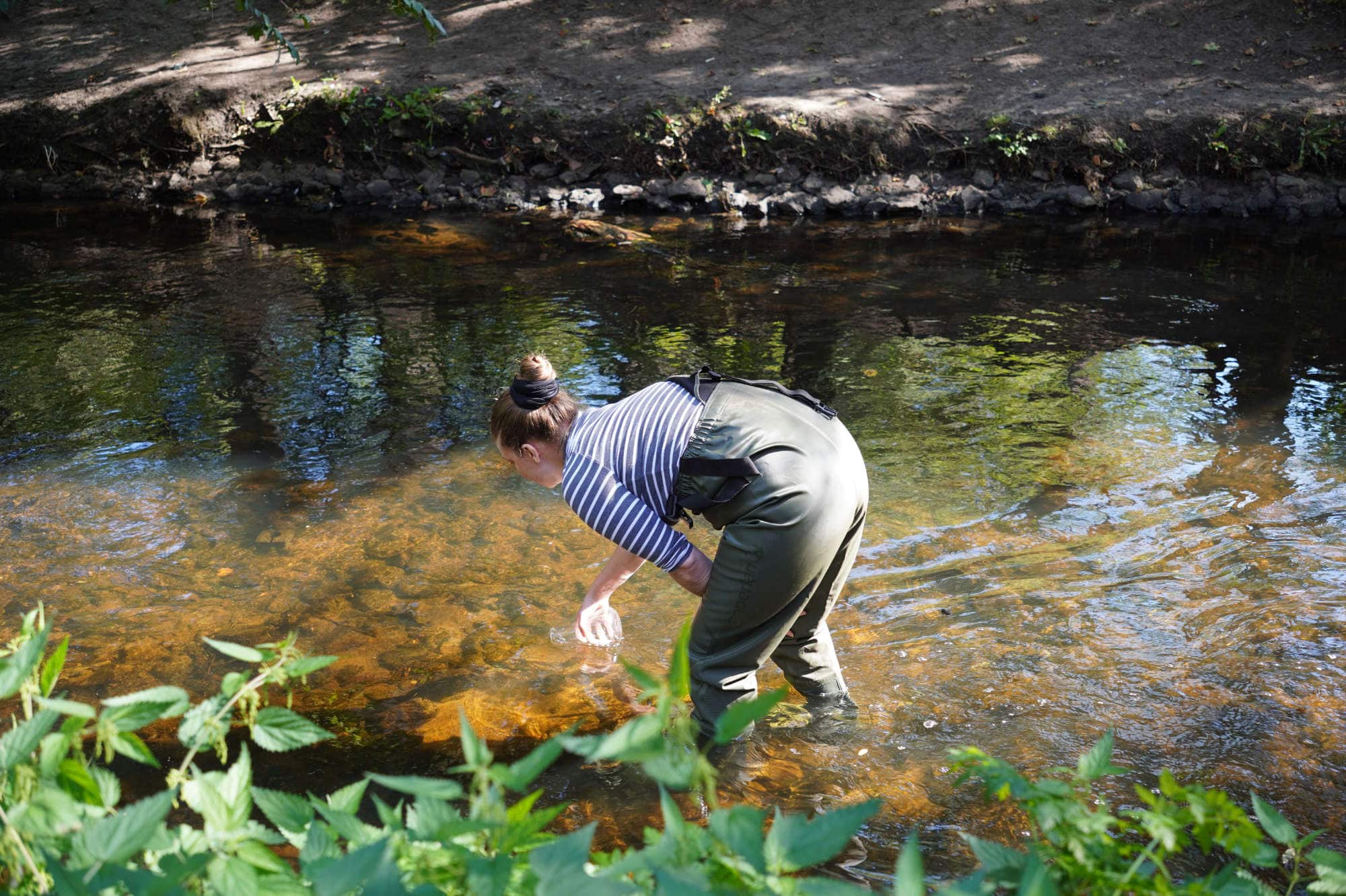a woman standing in a river in waders