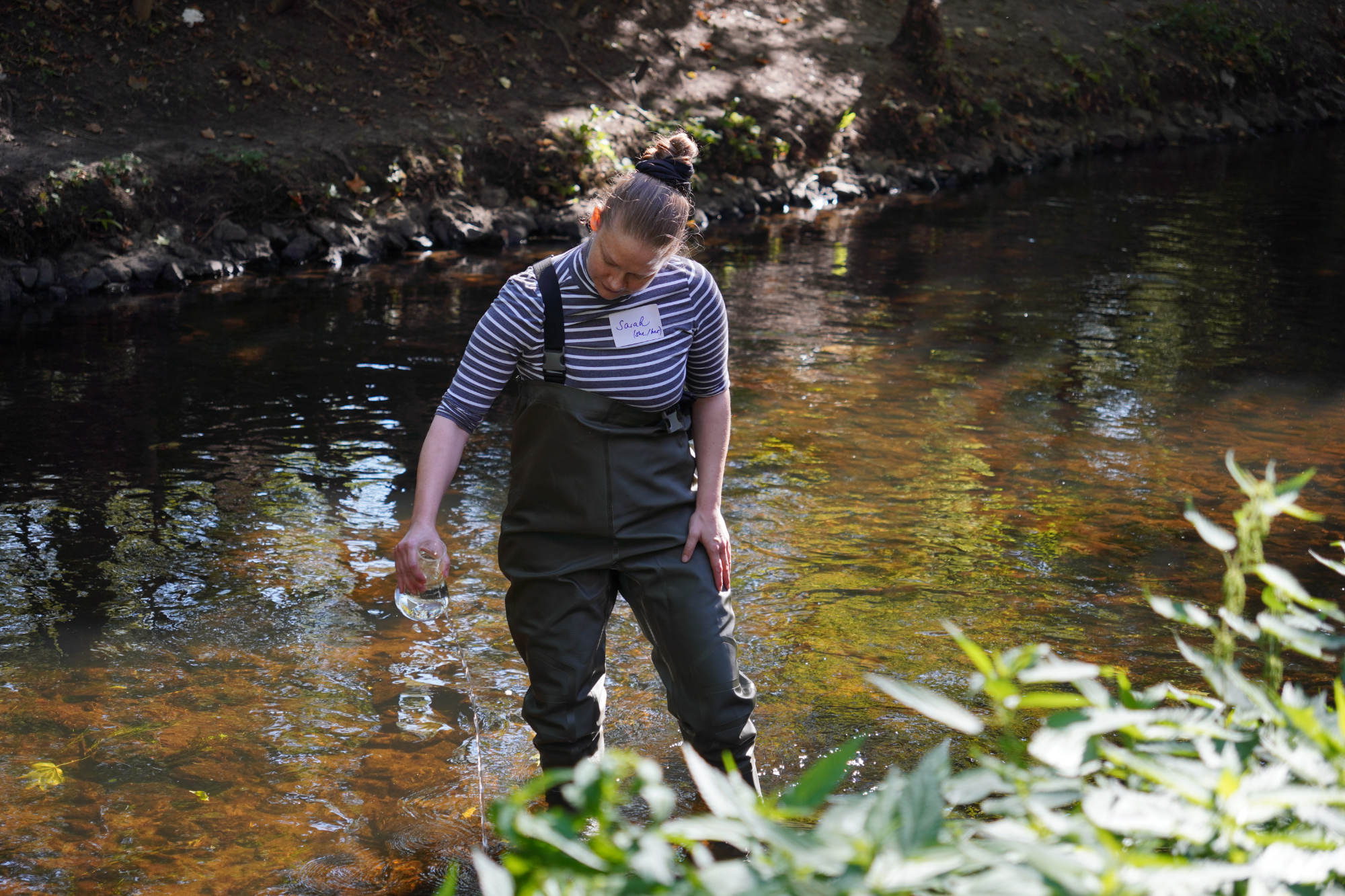 a woman standing in a river in waders