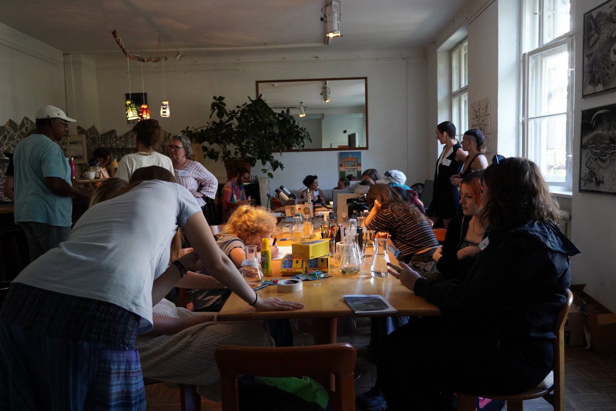 people sitting around a table with flask and microscopes, drawing and talking