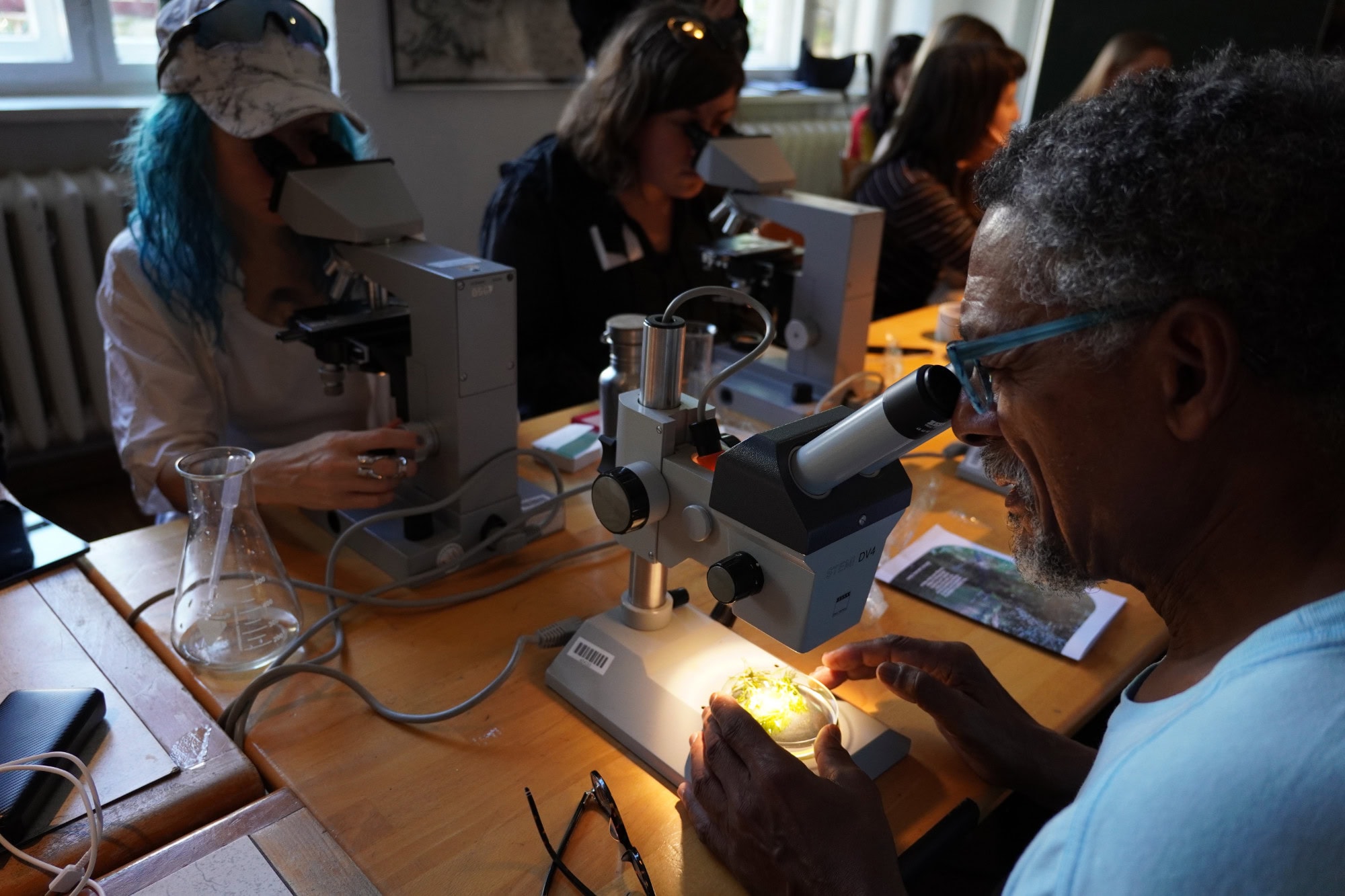 group of people sitting and looking through microscopes